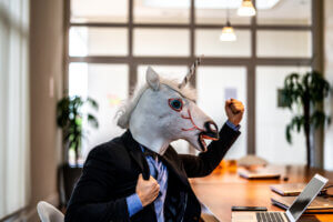 UX designer with Unicorn Mask raises a fist