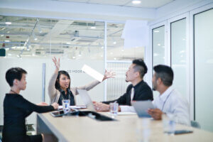 Asian businesswoman throws hands up at meeting