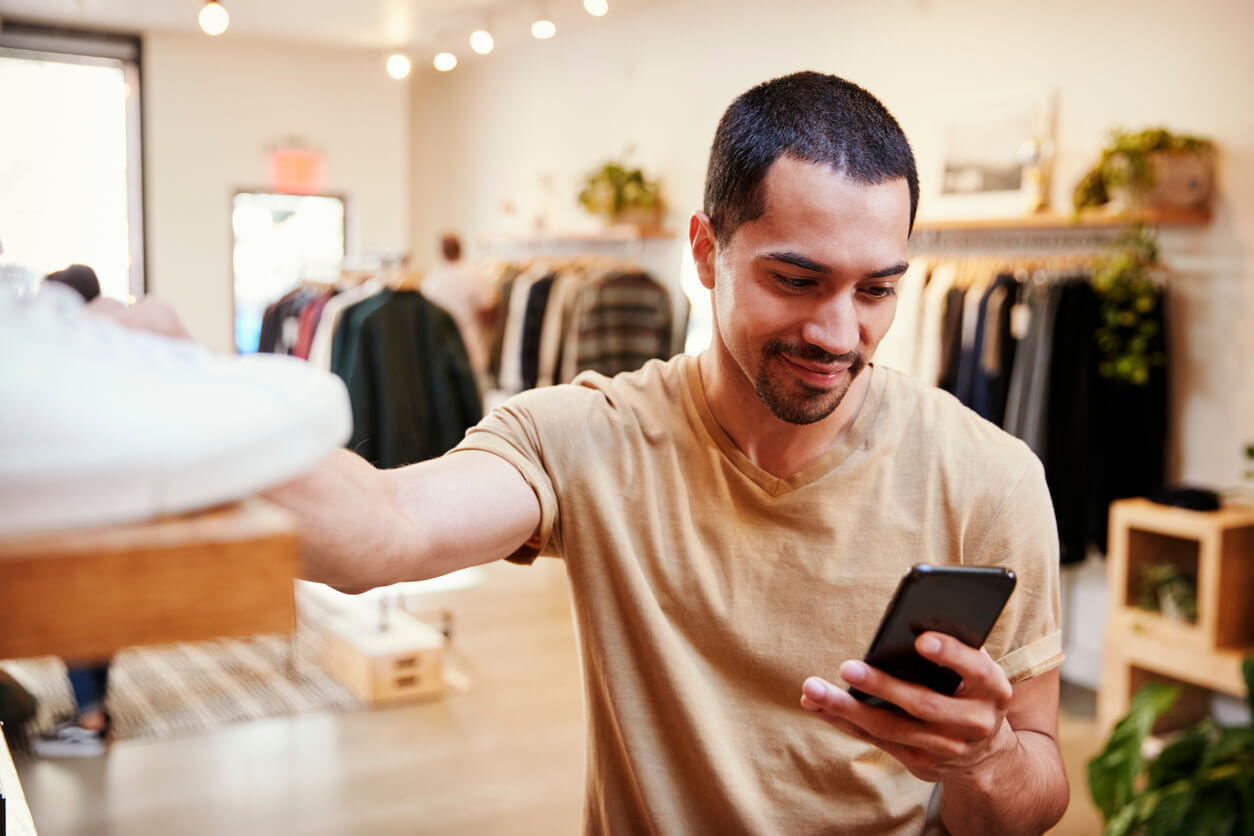 Smiling Hispanic man using smartphone in shop during a service safari