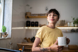 young Latina woman holding mug stares into distance looking bad ass
