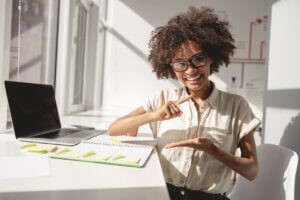 Deaf neurodiverse black woman using sign language at a computer desk