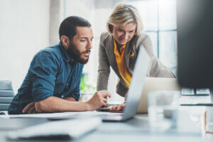 Man and woman coworkers collaborate with AI
