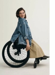adaptive clothing example woman in wheelchair smiles as jacket drapes over wheels from anthropologie