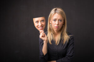 Woman holding persona mask of her happy face