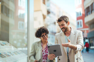two business people walking outside with tablet discussing UX