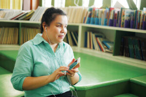 Blind Asian woman navigates their phone in a library