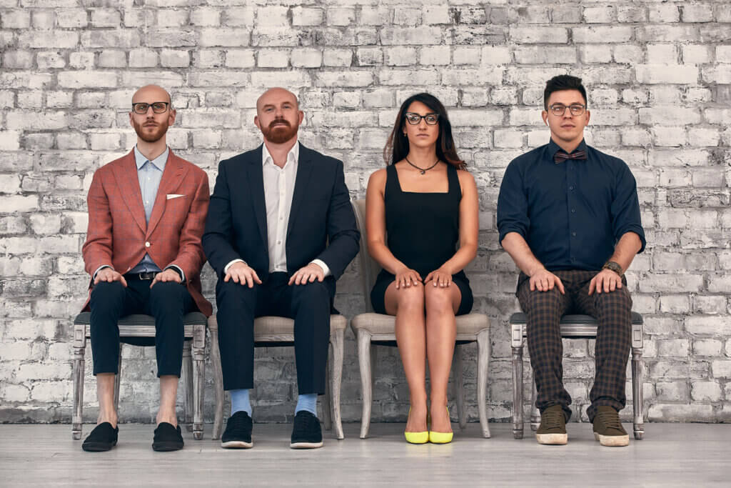 four team members sit side by side in a row