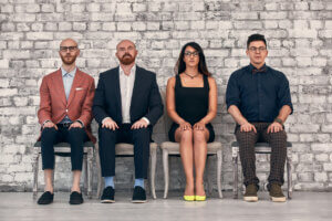 four team members sit side by side in a row