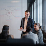 Diverse business team in a modern office during a meeting, discussing artificial intelligence strategy. Concept of AI innovation on white board